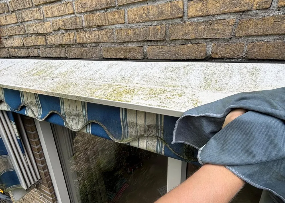 Dorpel en zonnewering met groene aanslag vóór reiniging